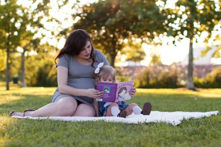 Pregnant mom reading book with daughter