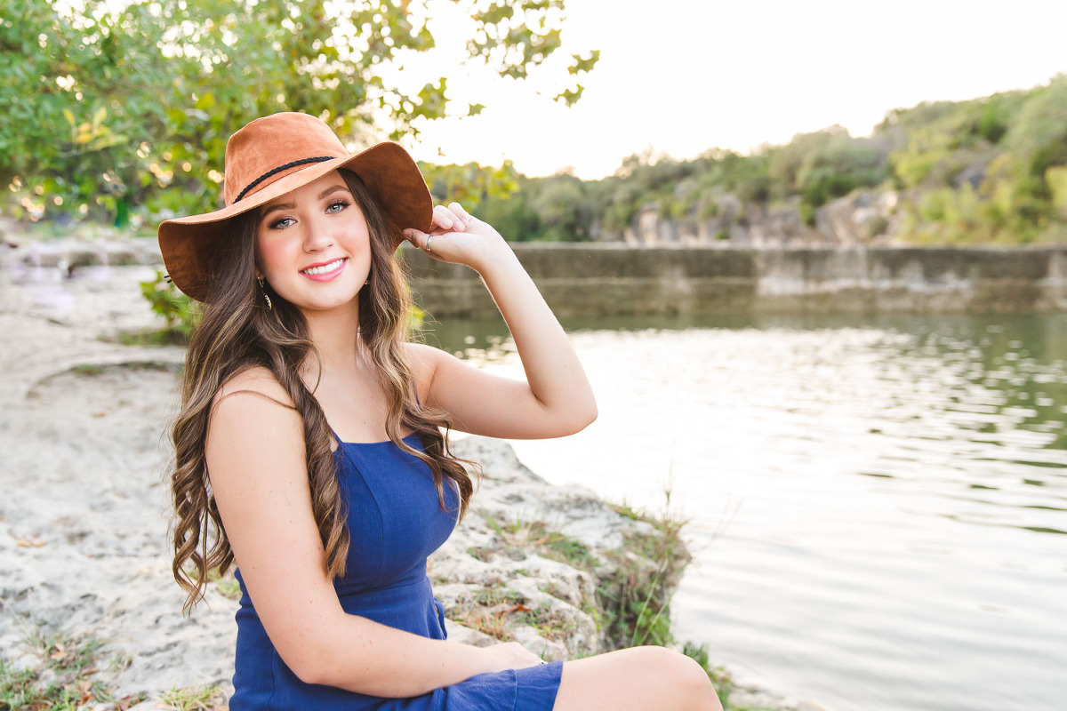 Senior High school girl sitting near water with hat